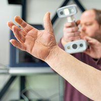 Een medewerker van het 3D-printbedrijf maakt een scan van een hand -- klik op de afbeelding om te vergroten