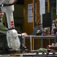 Twee studenten besturen robot en bewerken hout -- klik op de afbeelding om te vergroten