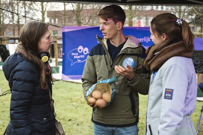Minne Baukema en Hester Schilt, initiatiefnemers van Onze Markt, tonen een zak aardappelen met een eerlijke prijs en lichten hun initiatief toe.