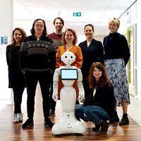 Het onderzoeksteam poseert met sociale robot Memo in hun midden -- klik op de afbeelding om te vergroten
