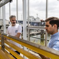 Jasper van Houcke en Christos Latsos in laboratorium met haven op de achtergrond -- klik op de afbeelding om te vergroten
