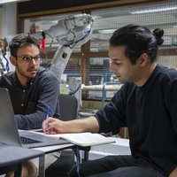 Two students discuss while working on a laptop -- klik op de afbeelding om te vergroten
