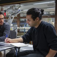 Two students discuss while working on a laptop -- klik op de afbeelding om te vergroten