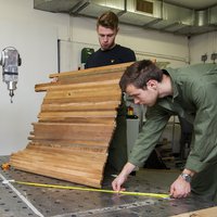 Twee studenten voeren metingen uit en bewerken houten planken -- klik op de afbeelding om te vergroten