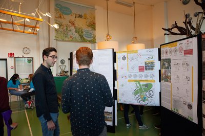 Studenten overleggen voor wand met infographics tijdens de Design Week in Maastricht -- klik op de afbeelding om te vergroten