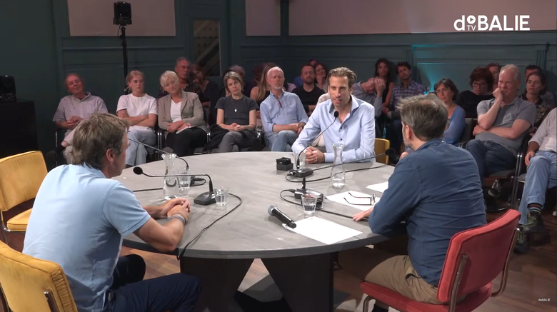 Lector Gideon Spanjar heeft het woord aan tafel bij De Koplopers. Naast hem moderator Teun van de Keuken en tegenover hem Nico Tillie van de TU Delft.