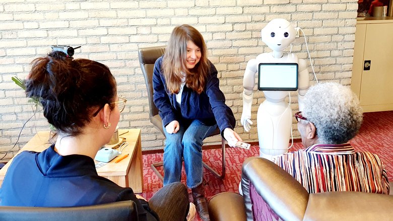 Een proefpersoon gaat onder begeleiding in gesprek met een robot voor het onderzoeksproject Robotstorie.