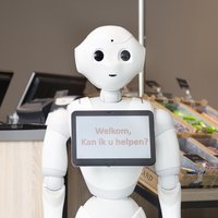De sociale robot met op zijn tablet de tekst "Welkom, kan ik u helpen?" -- klik op de afbeelding om te vergroten
