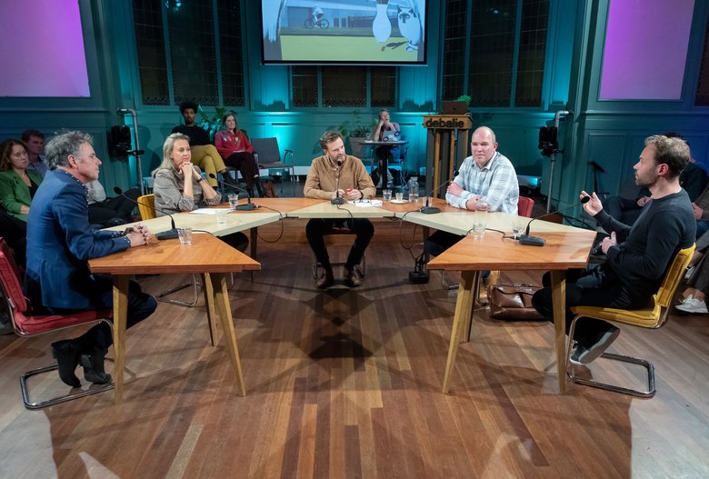 Gasten van De Koplopers zitten aan tafel om te debatteren, aan tafel van links naar rechts: Adriaan Geuze, Elisabeth Post, Teun van de Keuken, Cees-Jan Pen, Merten Nefs.