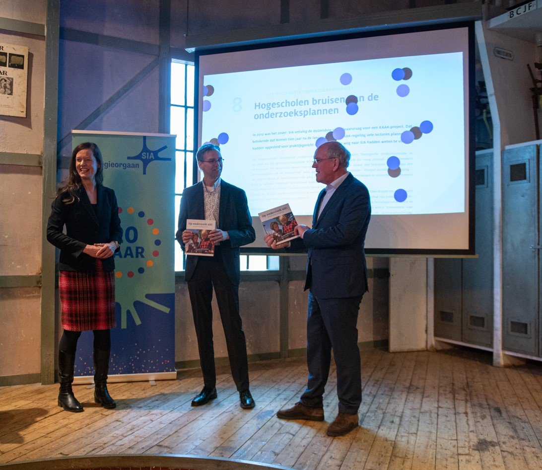 SIA-directeur reikt de eerste exemplaren van het boek Op onderzoek uit! uit aan scheidend directeur Richard Slotman en secretaris van de ROM's Marcel Kleijn