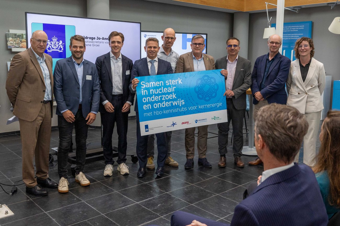 Staatssecretaris De Bat, voorzitter CvB HZ university of applied sciences en andere betrokkenen met bord met daarop ; Samen sterk in nucleair onderzoek en onderwijs' met een