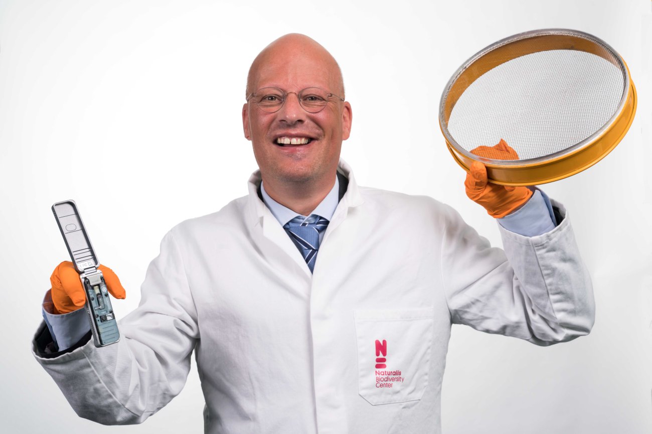 Man in witte doktersjas houdt telefoon en pvc-ring omhoog