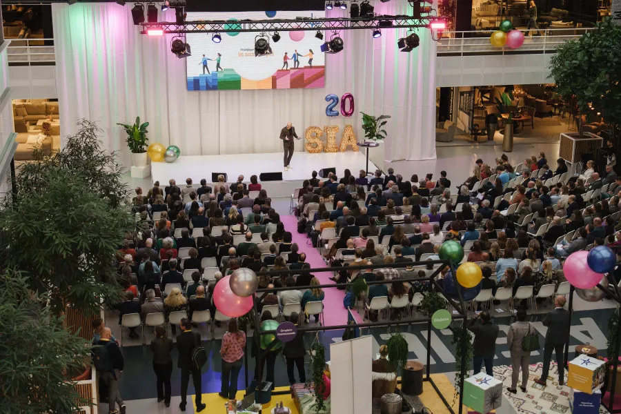 Overizchtsfoto van publiek dat luistert naar spreker op podium