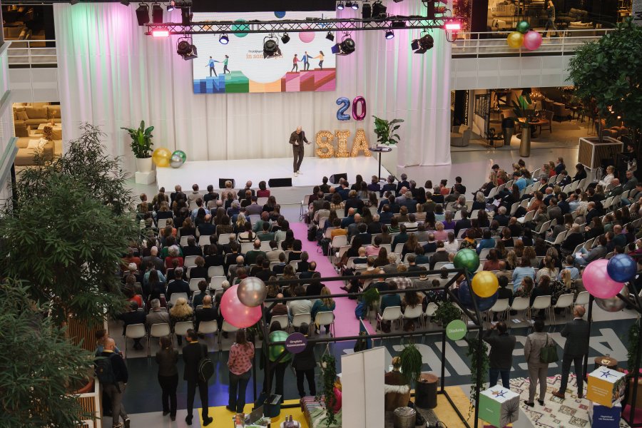 Overizchtsfoto van publiek dat luistert naar spreker op podium