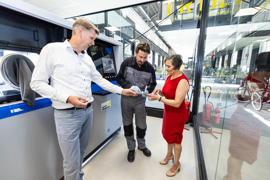 Vrouw en 2 mannen bekijken stuk metaal